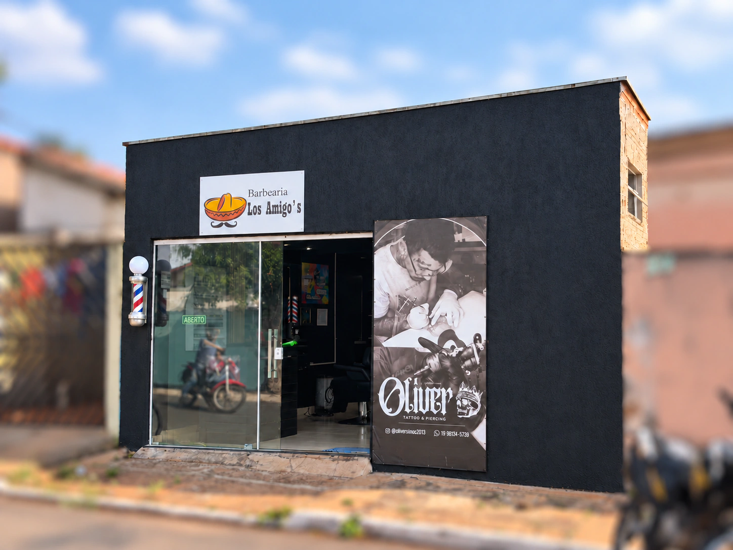 Fachada com porta de vidro e painel Oliver Tattoo junto à entrada