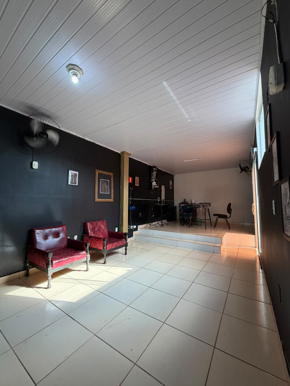 Interior do estúdio com duas poltronas vermelhas e a área de tatuagem ao fundo