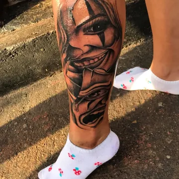 Tatuagem chicano preto e cinza de máscaras de palhaço na panturrilha