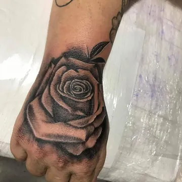 Tatuagem realismo preto e cinza de rosa na mão