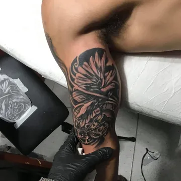 Tatuagem preto e cinza de pássaro com relógio e engrenagens no braço