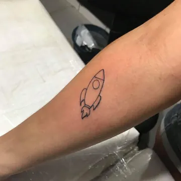 Tatuagem fineline de foguete no antebraço