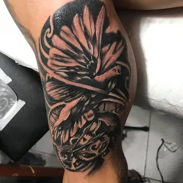Tatuagem preto e cinza de pássaro com relógio na parte interna do braço