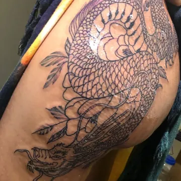 Tatuagem fineline de dragão oriental na coxa