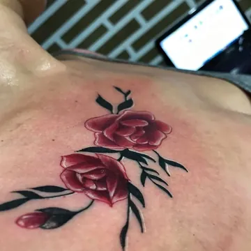 Tatuagem colorida de rosas vermelhas no peito