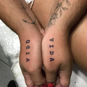 Tatuagem lettering da palavra Vida na lateral de duas mãos