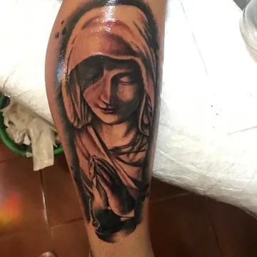 Tatuagem realismo preto e cinza de Nossa Senhora rezando na panturrilha