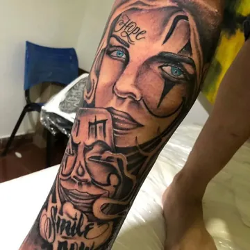 Tatuagem chicano preto e cinza de rosto feminino com lettering na perna