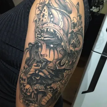Tatuagem preto e cinza de figura feminina com serpentes e caveiras no braço