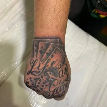 Tatuagem preto e cinza de cartas e dados com lettering na mão